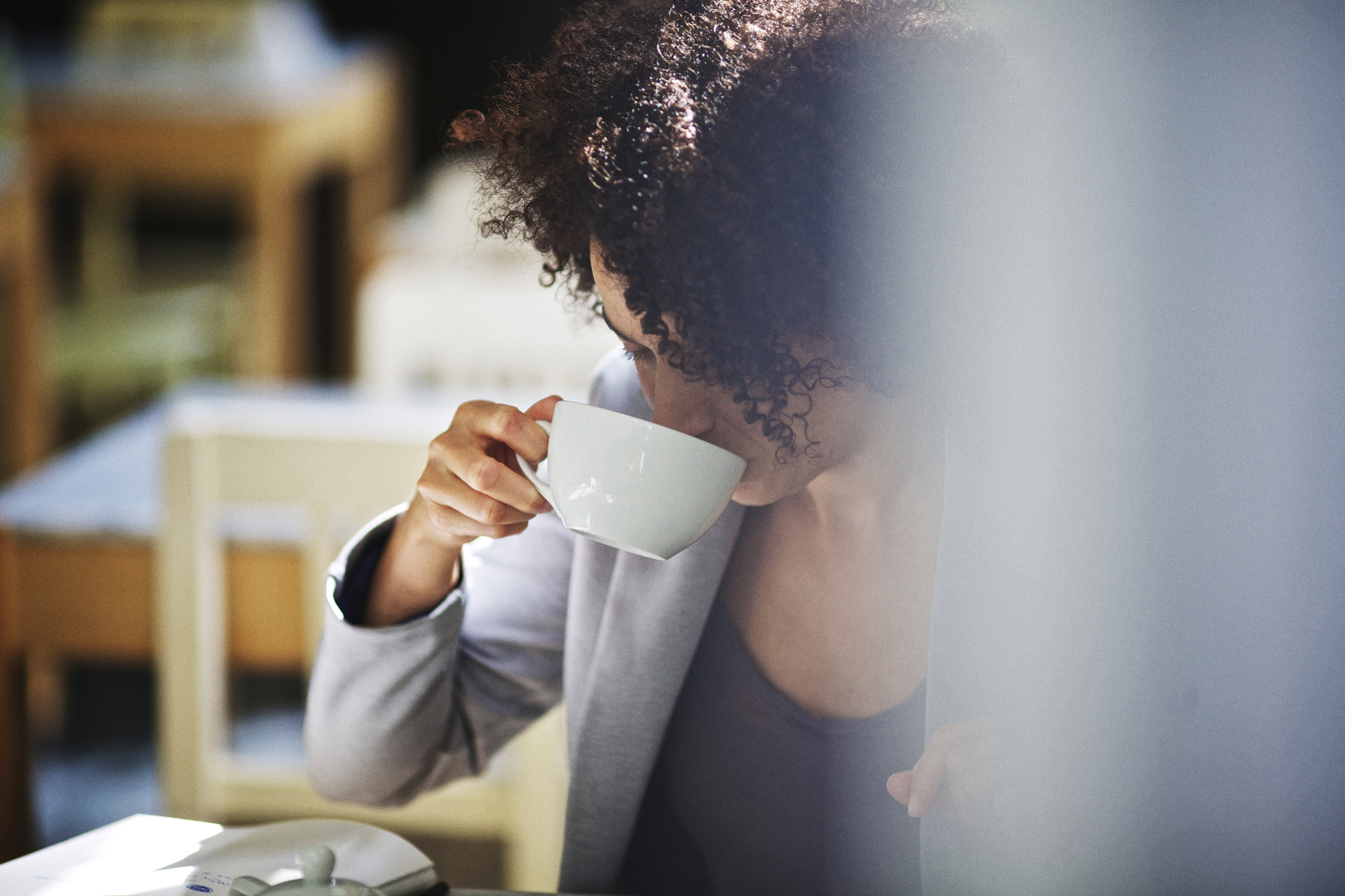 Vrouw neemt een slok koffie uit een wit kopje