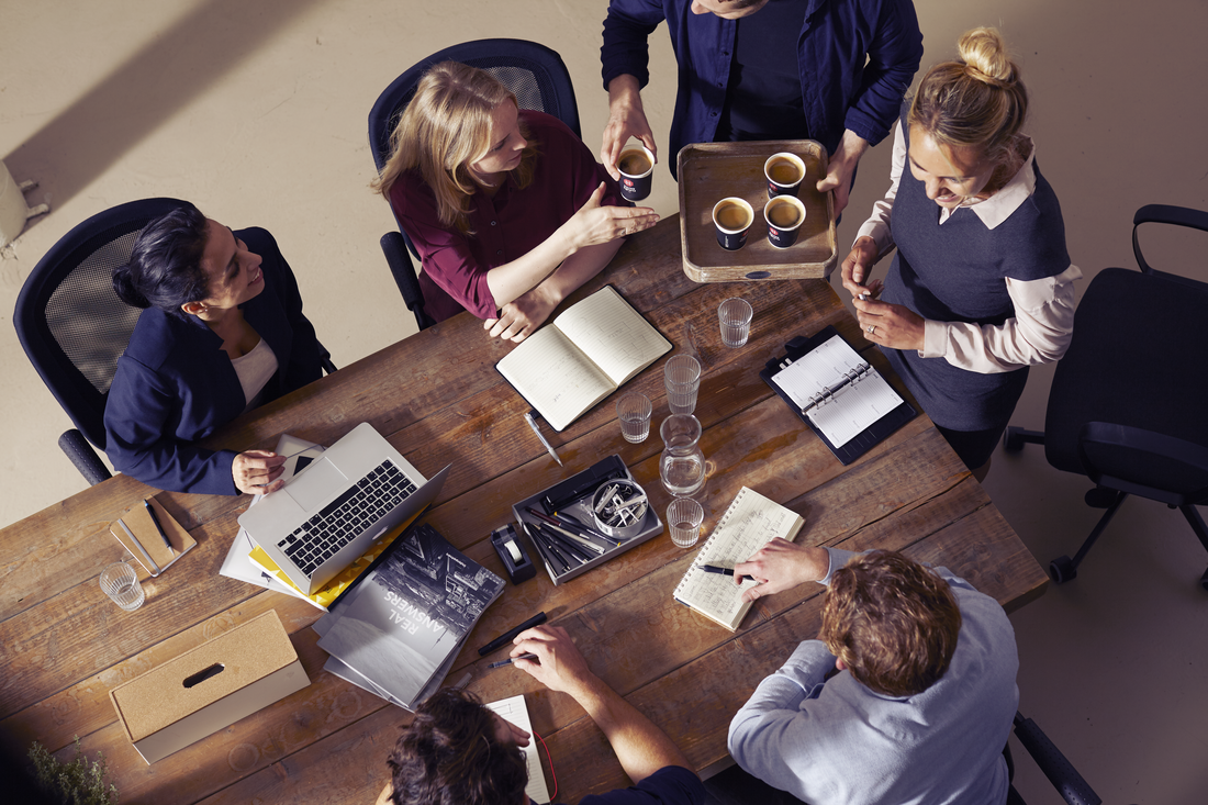 a group of people in a professional setting passing douwe egberts coffee around