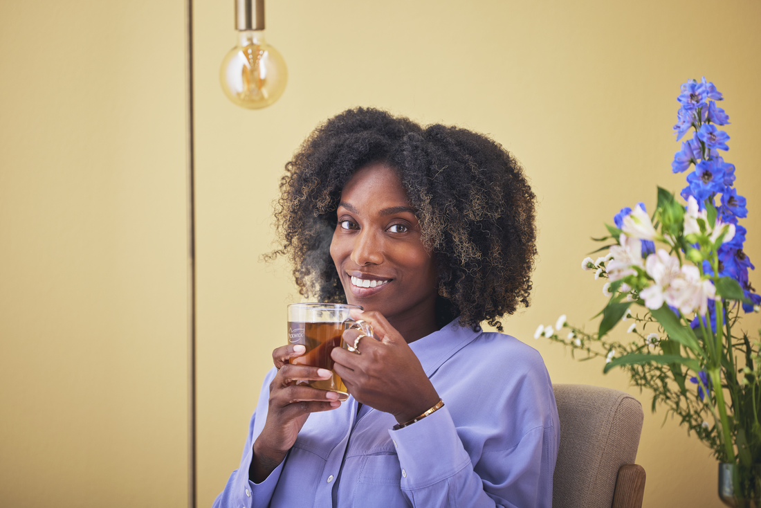 Lachende vrouw met een glas Pickwick thee die recht in de camera kijkt