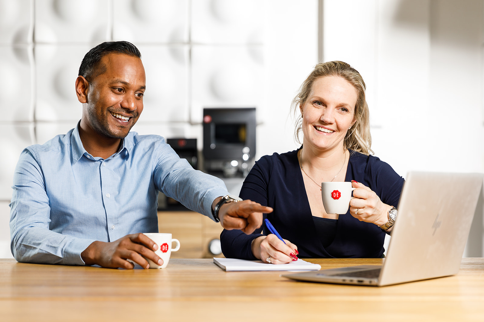 twee mensen achter een laptop die douwe egberts koffie drinken
